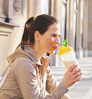 Almased im Shaker in der Hand einer jungen Frau